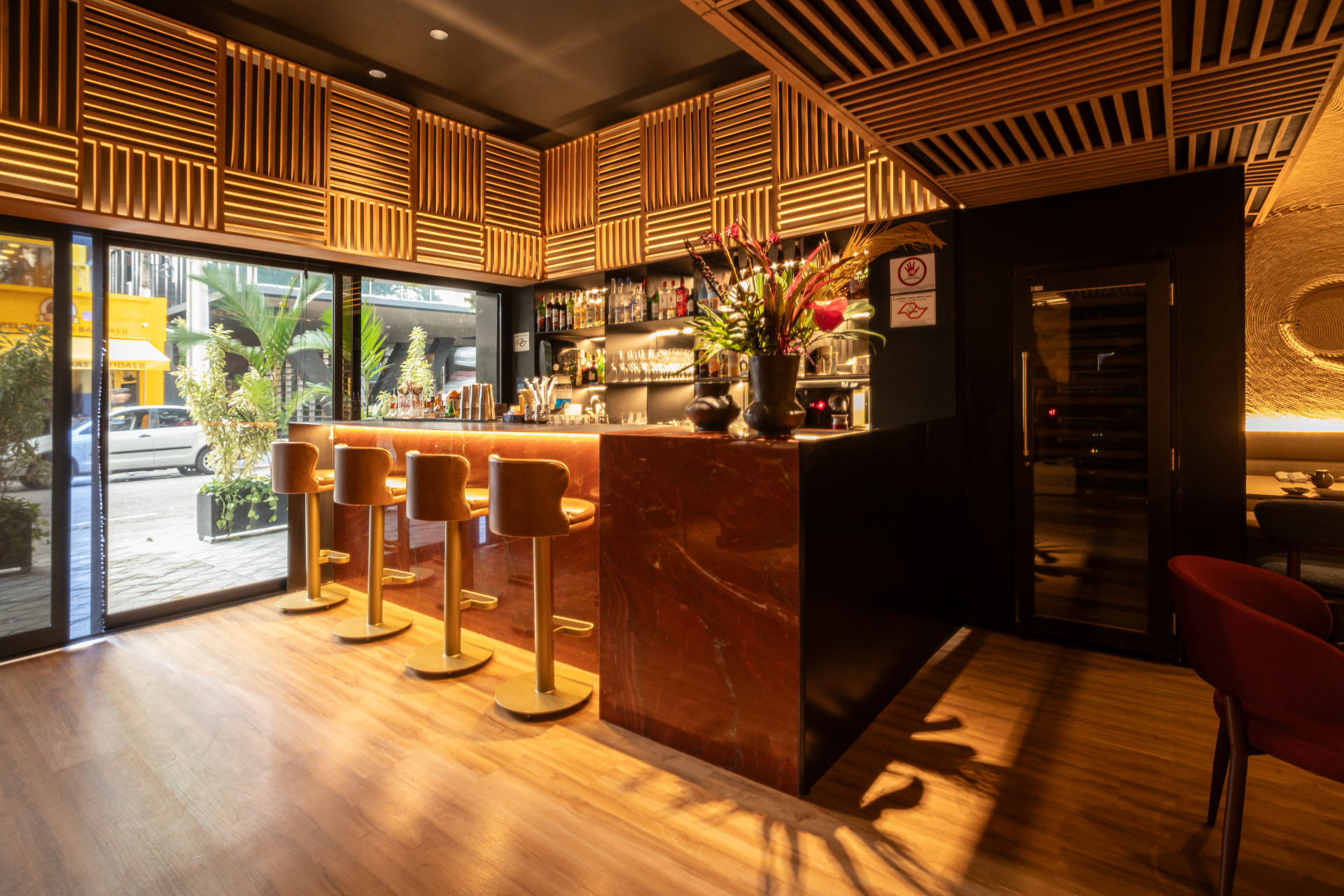 Bar do Kitchin Itaim com banquetas douradas e vista para a rua